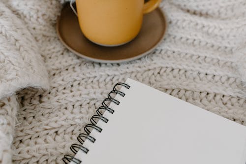 Free Close-Up Shot of a Spiral Notebook beside a Cup Stock Photo