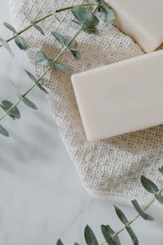 Aesthetic flat lay of a bar soap with eucalyptus on woven towel for spa and wellness.
