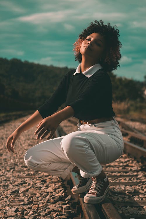Woman in Black Top Sitting on Train Track 