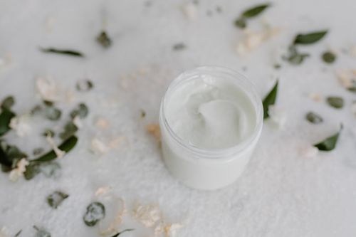 Free Aesthetic close-up of an open skincare cream jar surrounded by natural leaves, showcasing beauty. Stock Photo