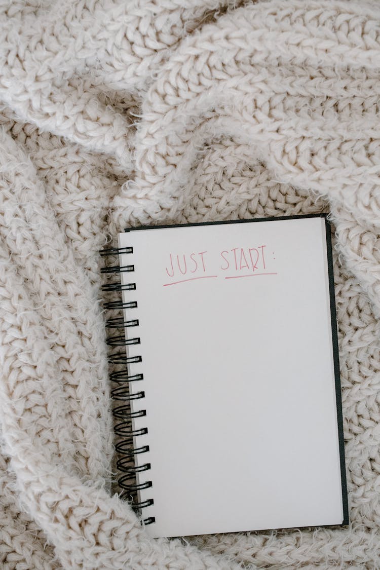 Open Notebook On White Knitted Fabric Close-Up Photo