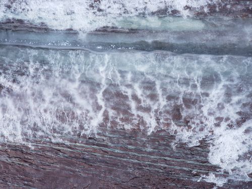 Free Drone photo capturing waves crashing over rocky shoreline in Quebec, Canada. Stock Photo
