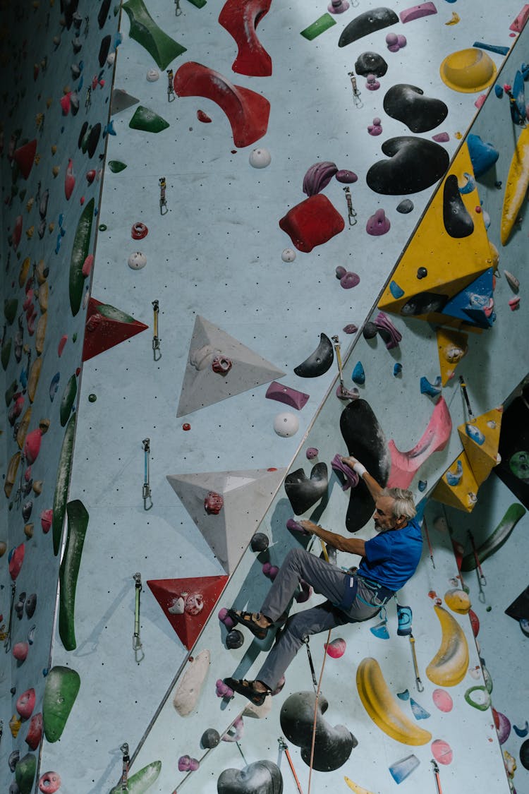 Strong Man In Blue Shirt Doing Rock Climbing On Wall