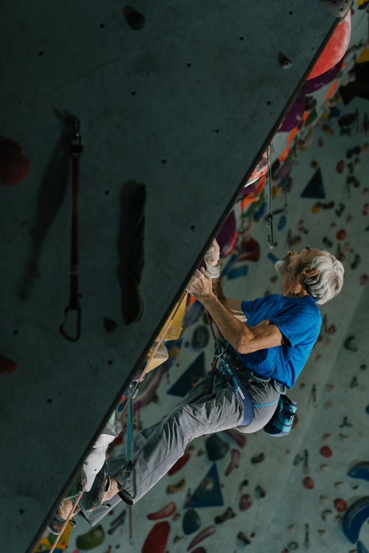 Strong Man In Blue Shirt Doing Rock Climbing On Wall