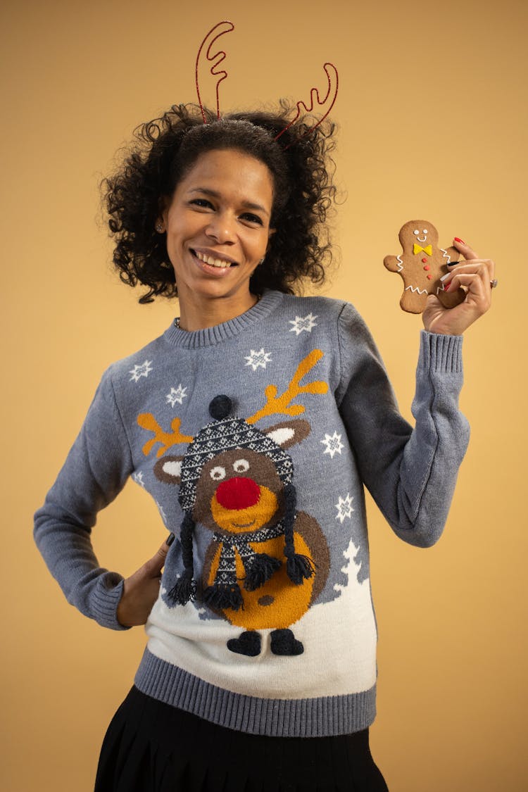 A Woman Wearing An Antler Headband Holding A Ginger Bread Cookie