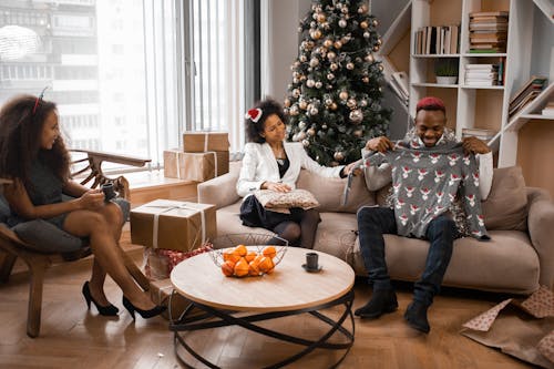 Women Looking at a Man Trying On a Christmas Sweater