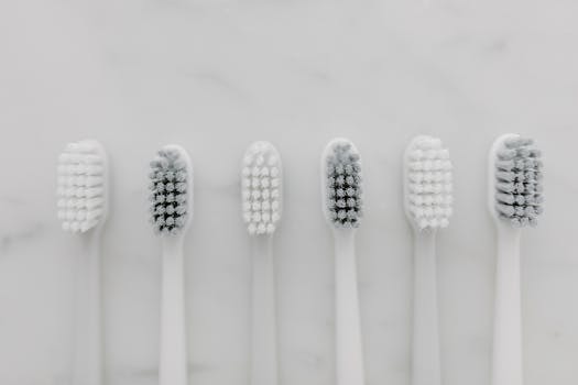 A clean, minimalist top view of six white toothbrushes on a marble surface.
