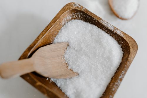 Free Close-up of coarse sea salt in a wooden bowl with a wooden scoop, perfect for culinary use. Stock Photo