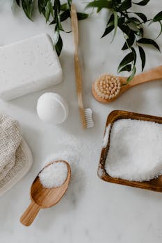 Top view of natural bath essentials including soap, brush, and bath salts on a white background.