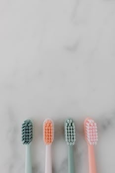 Four pastel-colored toothbrushes aligned on a marble surface, perfect for dental hygiene themes.