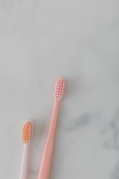 Two pink and white toothbrushes on a marble background, top view.