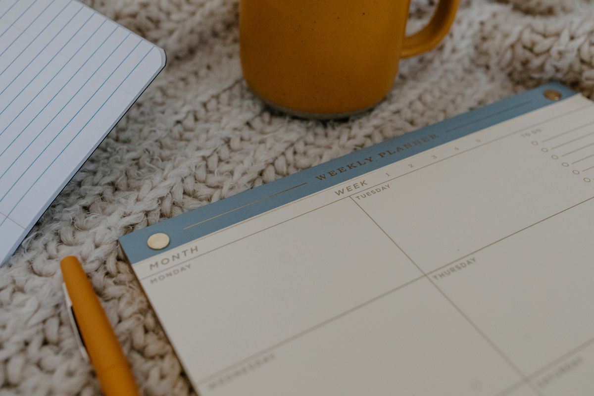 Planner semanal sem ano visível com caneta e caneca para organizar prioridades com calma