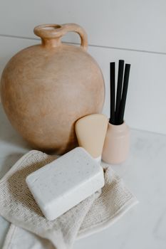 A serene display of bath essentials with bar soap and a clay pot on a knitted towel.