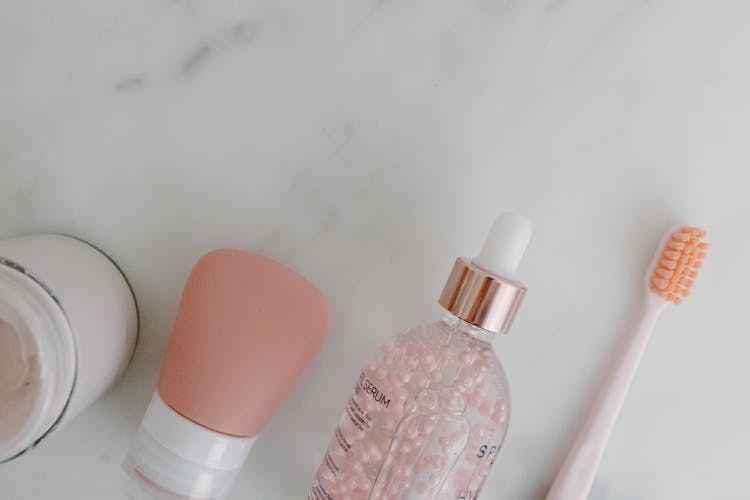 Cosmetic Products On White Surface Beside  A Toothbrush