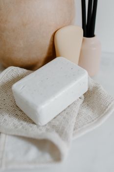 Elegant white soap on textured towel with vases in a serene setting.
