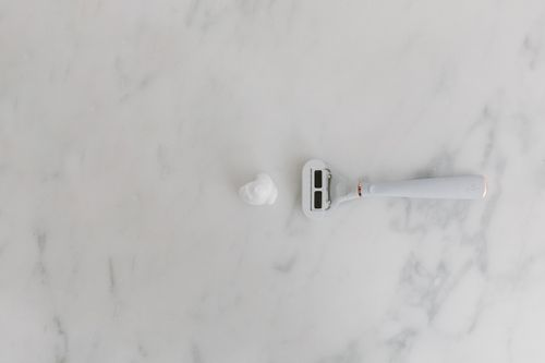 Free A minimalist scene with a shaving razor and foam on a marble background, offering copyspace. Stock Photo