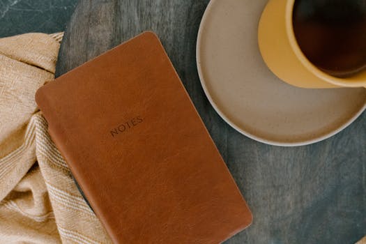 Top view of a leather notebook and coffee cup on a wooden table, perfect for productivity themes.