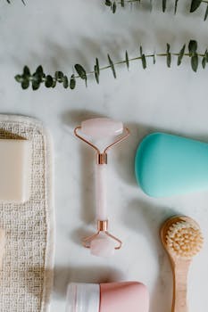 Aesthetic flat lay of skincare items including facial roller, brush, and soap on marble.