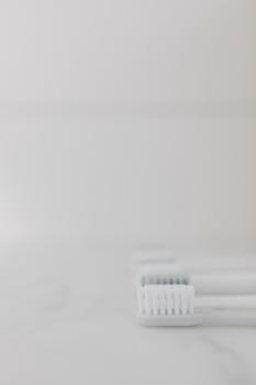 Vertical shot of white toothbrush heads on a marble surface, promoting dental hygiene.