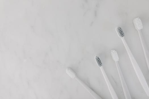 Elegant display of white toothbrushes on a marble surface, emphasizing hygiene and simplicity.