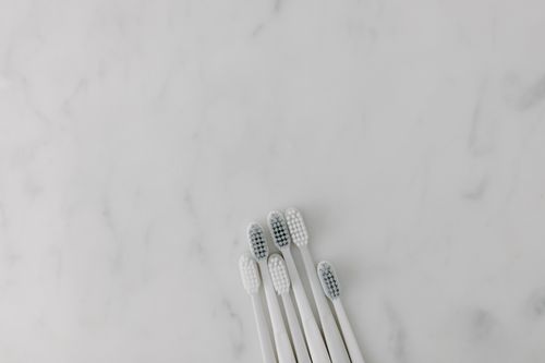 Free Five white toothbrushes arranged on a marble surface, offering a clean and minimalist aesthetic with ample copy space. Stock Photo