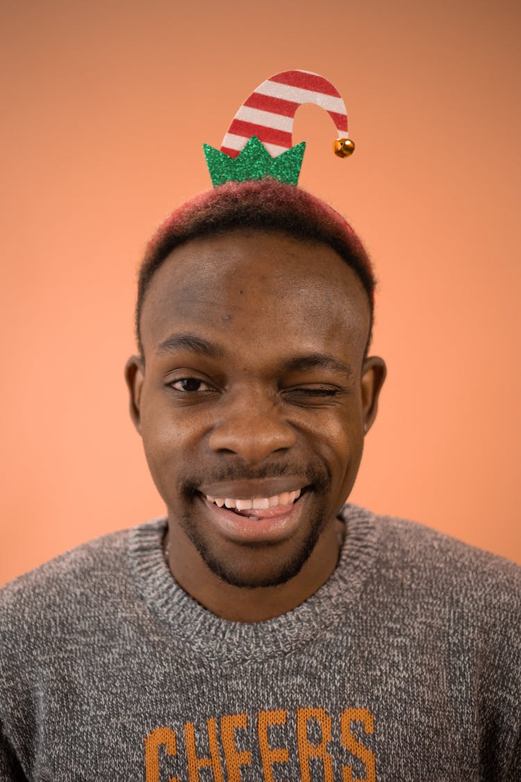 Portrait Of A Man Making A Funny Face And Wearing A Tiny Christmas Hat