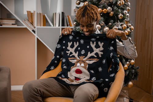 A Smiling Man Holding a Reindeer Sweater