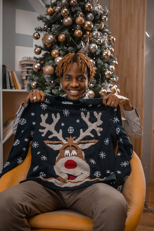 A Smiling Man Holding a Reindeer Sweater