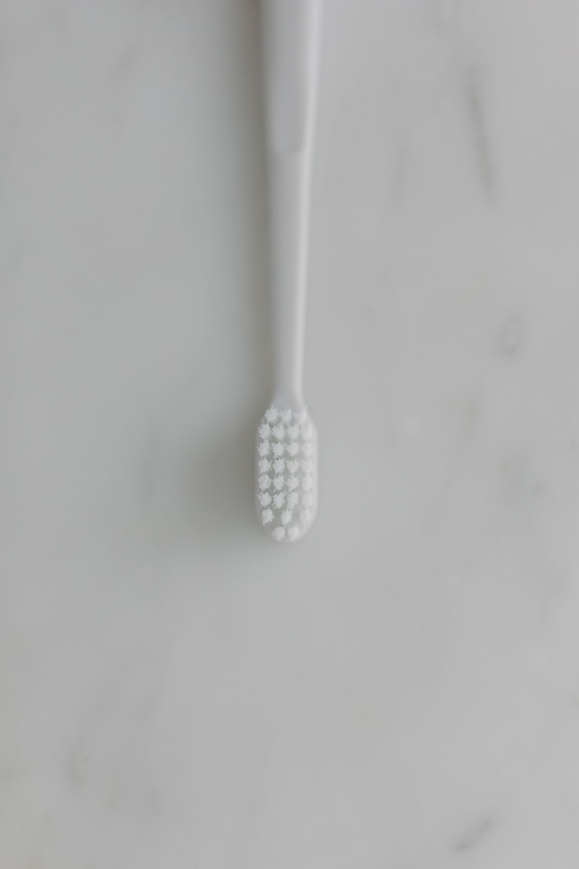 Minimal toothbrush arranged on a clean white bathroom surface