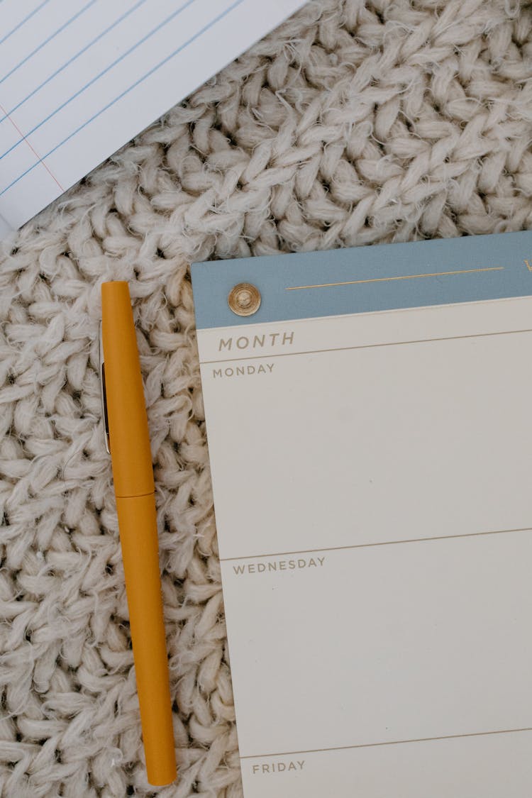 A Pen Beside A Weekly Planner