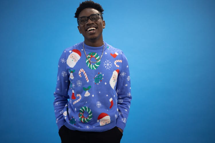 A Man With Eyeglasses Wearing A Blue Ugly Christmas Sweater