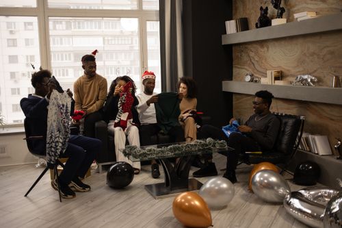 Free Group of friends exchanging gifts indoors during the holiday season, celebrating joyfully. Stock Photo