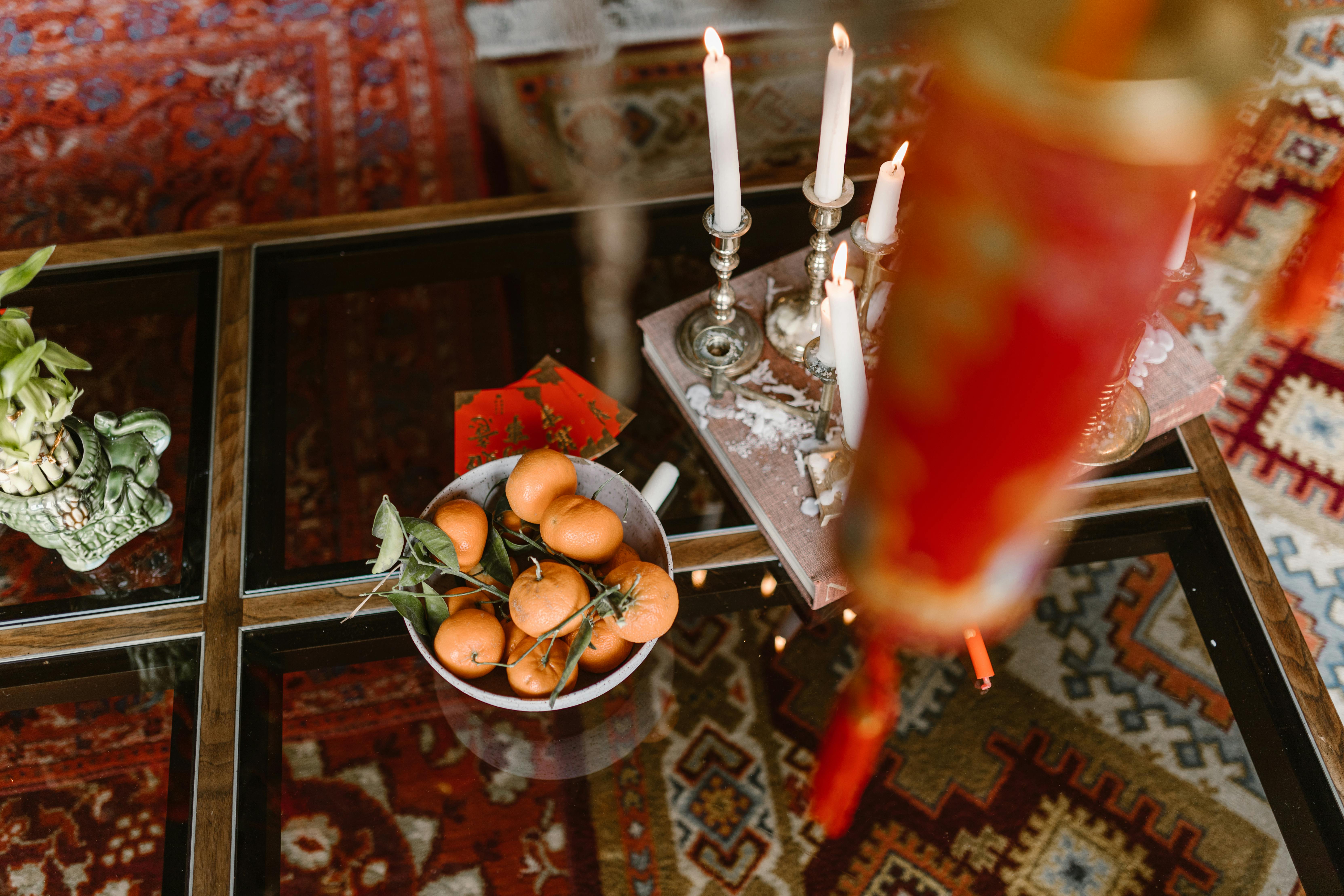 Free Festive Chinese New Year table with oranges, red envelopes, and candles on a glass table. Stock Photo