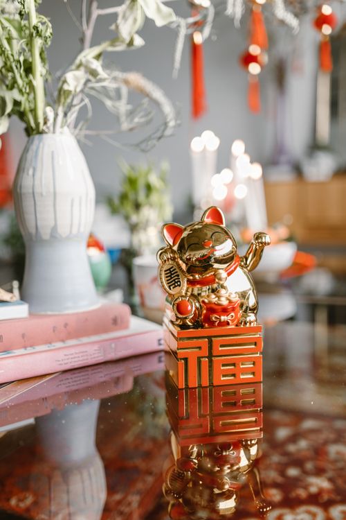 Free Golden Maneki Neko figurine on table with festive decor and plants, perfect for celebrations. Stock Photo