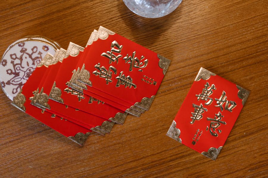 Red gift envelopes fanned out on a wooden table — photo by RDNE Stock project on Pexels
