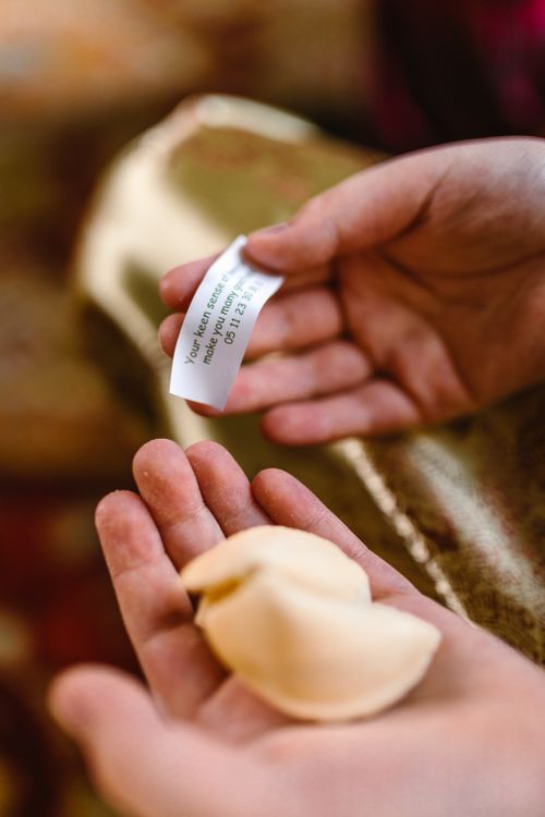 Free Close-up of hands holding a fortune cookie with a message, symbolizing tradition and luck. Stock Photo