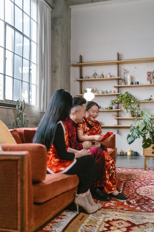 Family Sitting on red Sofa Near Window