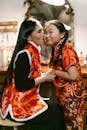 Happy Mother Kissing Daughter on Her Cheek Wearing Traditional Chinese Clothes
