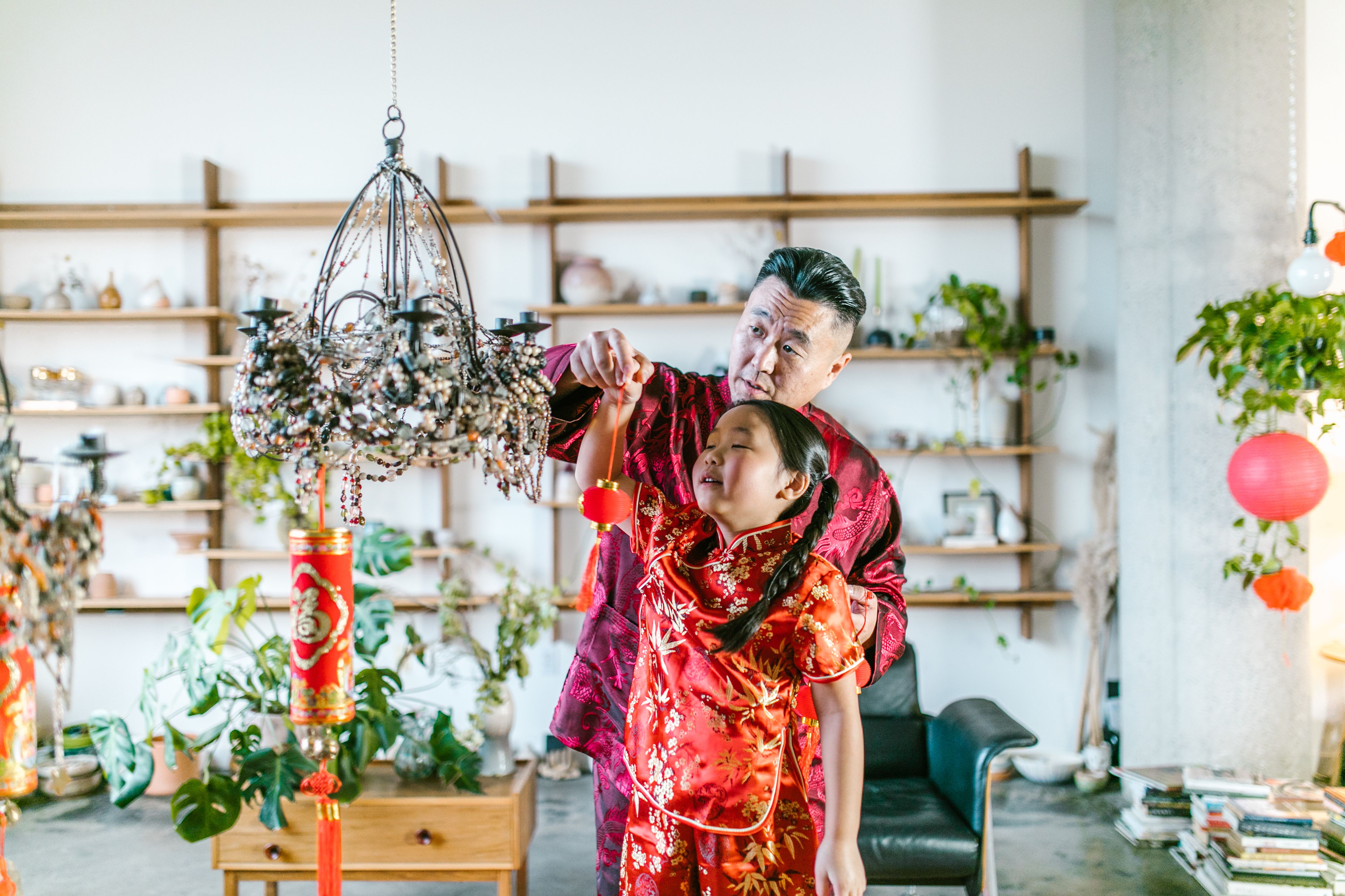 Elderly Man Hanging a Red Lantern with his Granddaughter