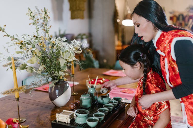 Mother And Daughter Serving Themselves A Cup Of Tea