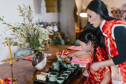 Free A mother and daughter in traditional clothes preparing a tea ceremony indoors. Stock Photo