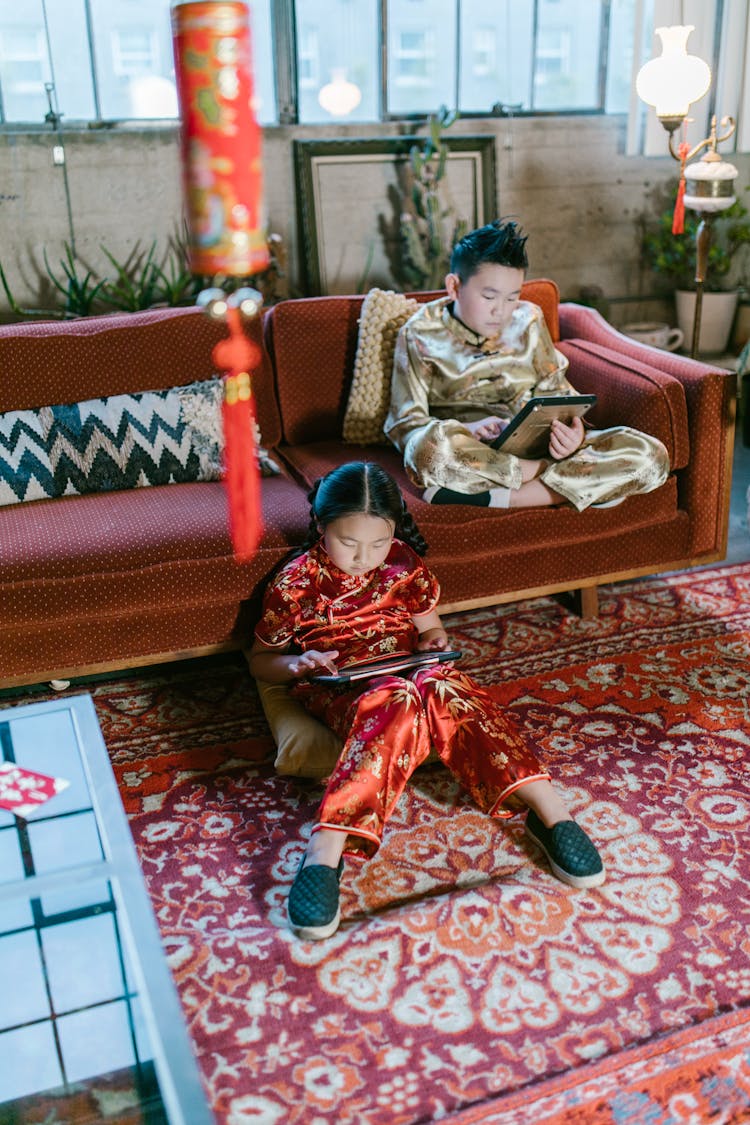 Children Using Tablets While Sitting On A Couch