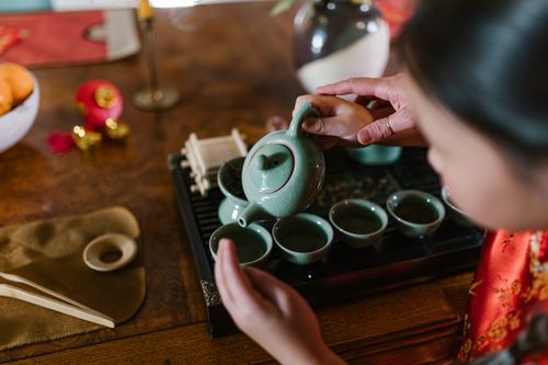 Free Young child guided in traditional tea pouring, embracing cultural rituals indoors. Stock Photo