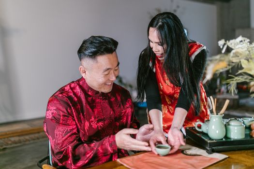 A Woman Serving Tea to a Man Sitting at the Table