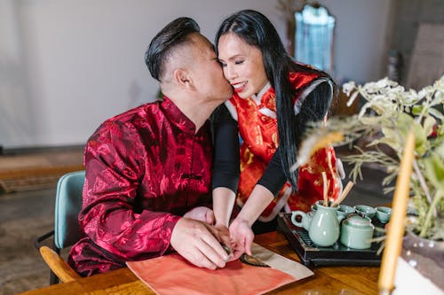 An affectionate couple in traditional clothing enjoys a loving moment during a tea ceremony.