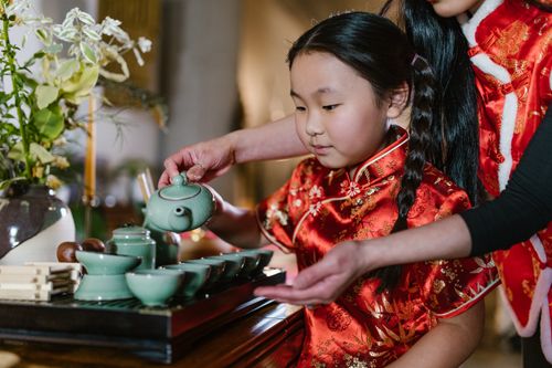 Free A young girl in traditional clothing learning a tea ceremony with her mother assisting, showcasing cultural heritage. Stock Photo