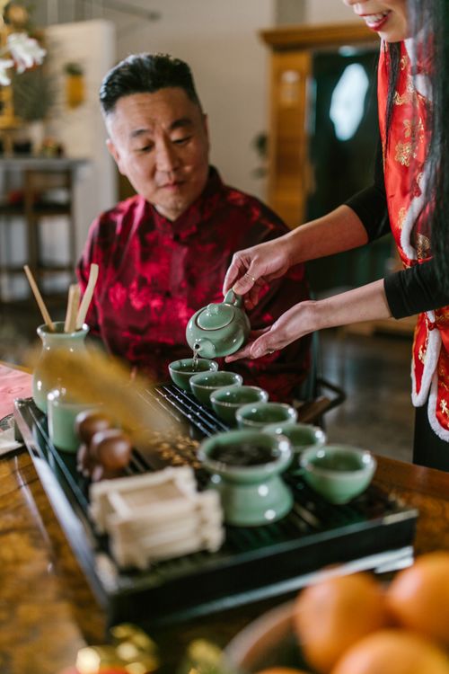 Free Asian man enjoying a traditional tea ceremony indoors with smiling server. Stock Photo