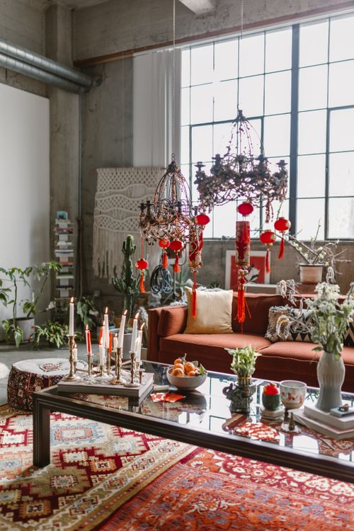 Free Stylish bohemian living room with cultural decor and vibrant red accents. Stock Photo