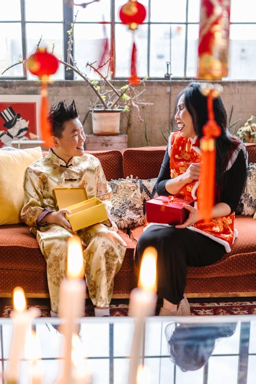 Mother and son exchanging gifts while seated on a couch, surrounded by Chinese New Year decorations.