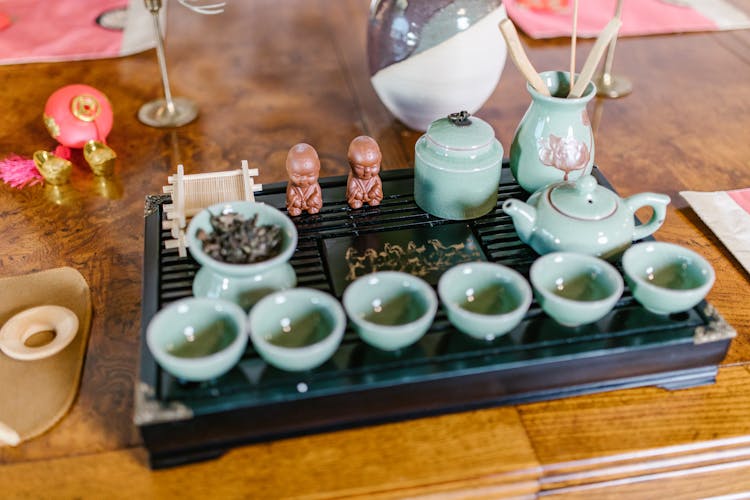 A Tea Set On A Black Tray With Miniatures 